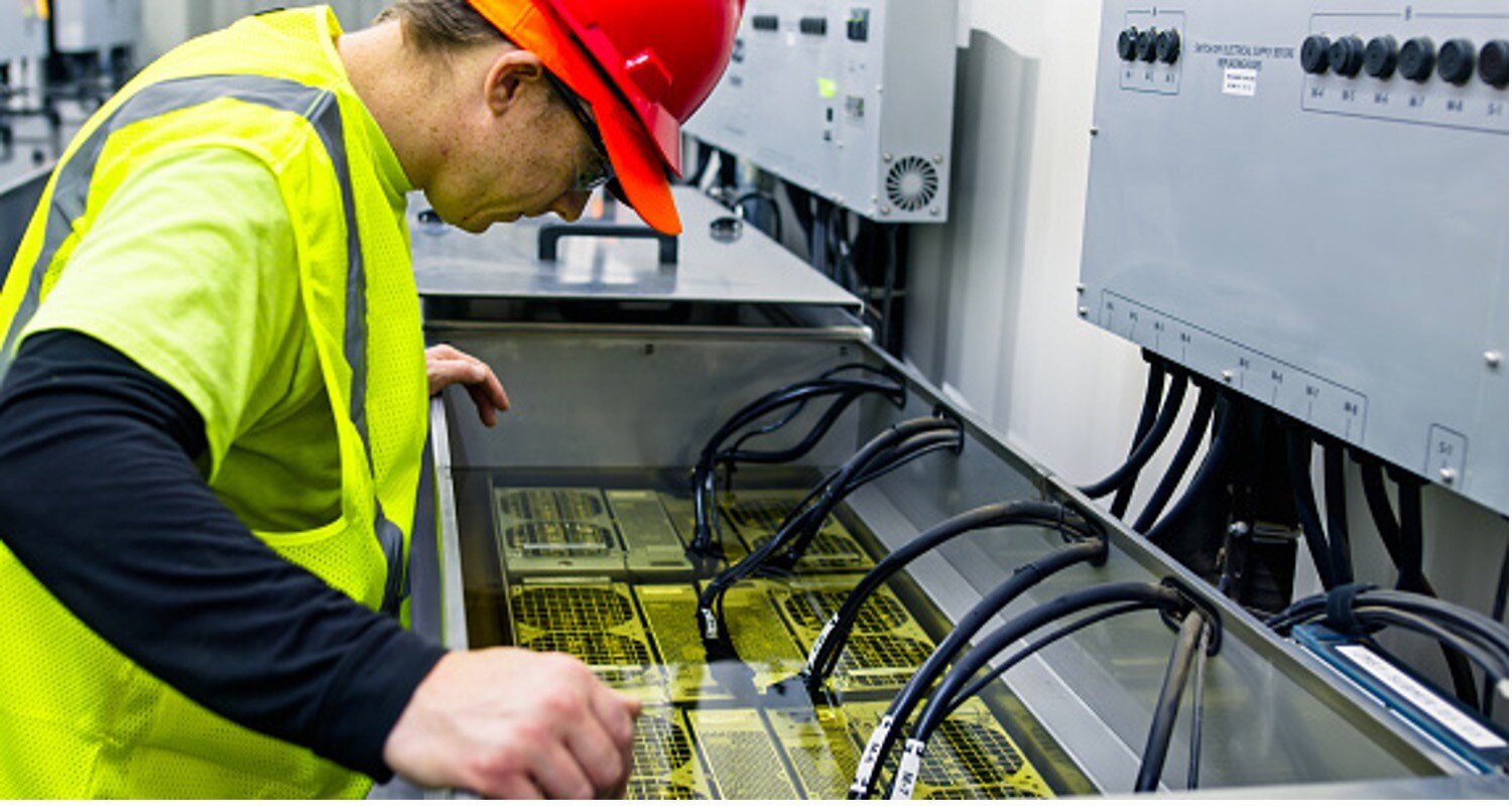 A technician observing computer servers in an immersion cooling tank