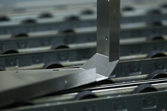 metal bracket resting on a conveyor belt with rollers in a Texas manufacturing factory