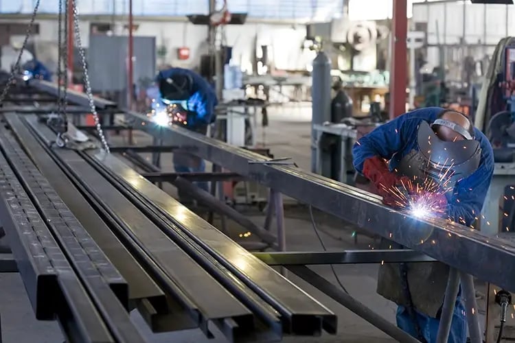 Workers welding in a steel fabrication workshop